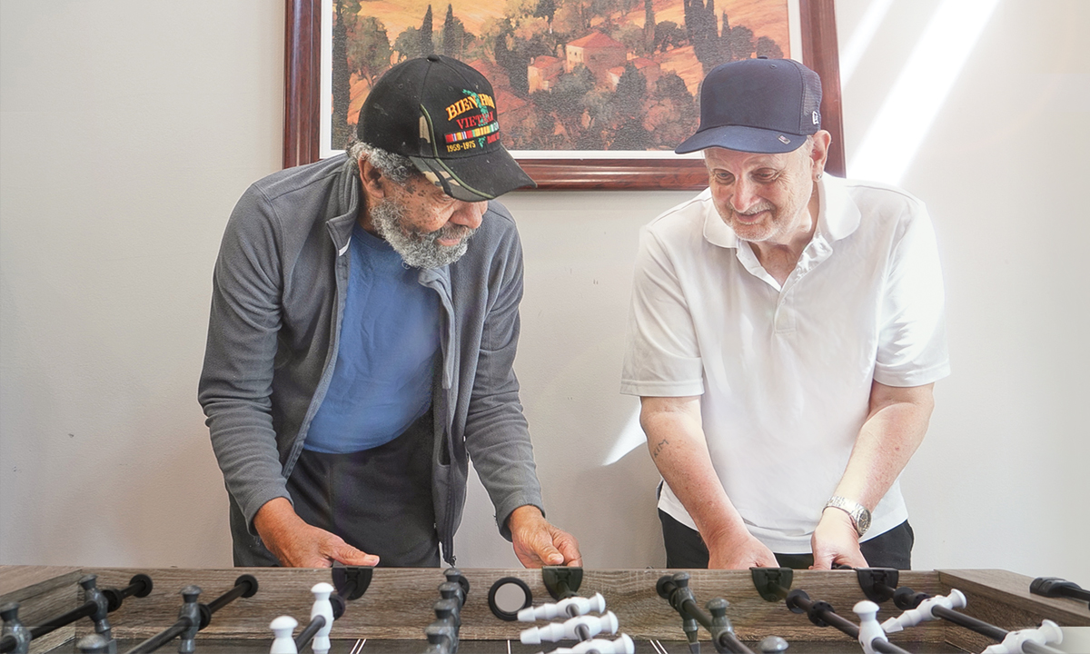 Two older men playing fooseball